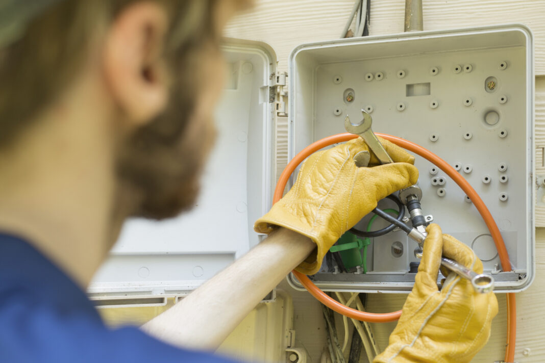 Young adult repairman works on cable service to home.