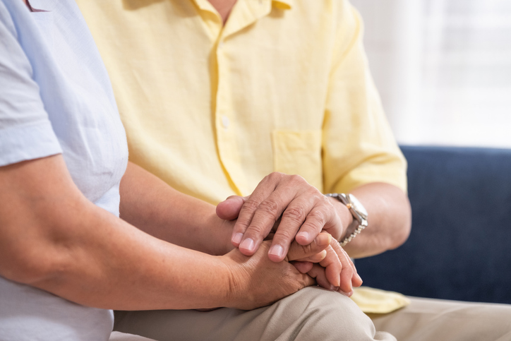 Close up Asian senior couple encouraging together by holding hand each other at sofa in living room at home.Happy retirement lifestyle.aging at home