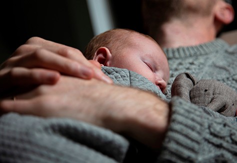 A father holding his baby son on his chest. Family bonding. Fatherhood